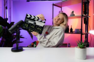 une femme assise à une table tenant un clap de cinéma