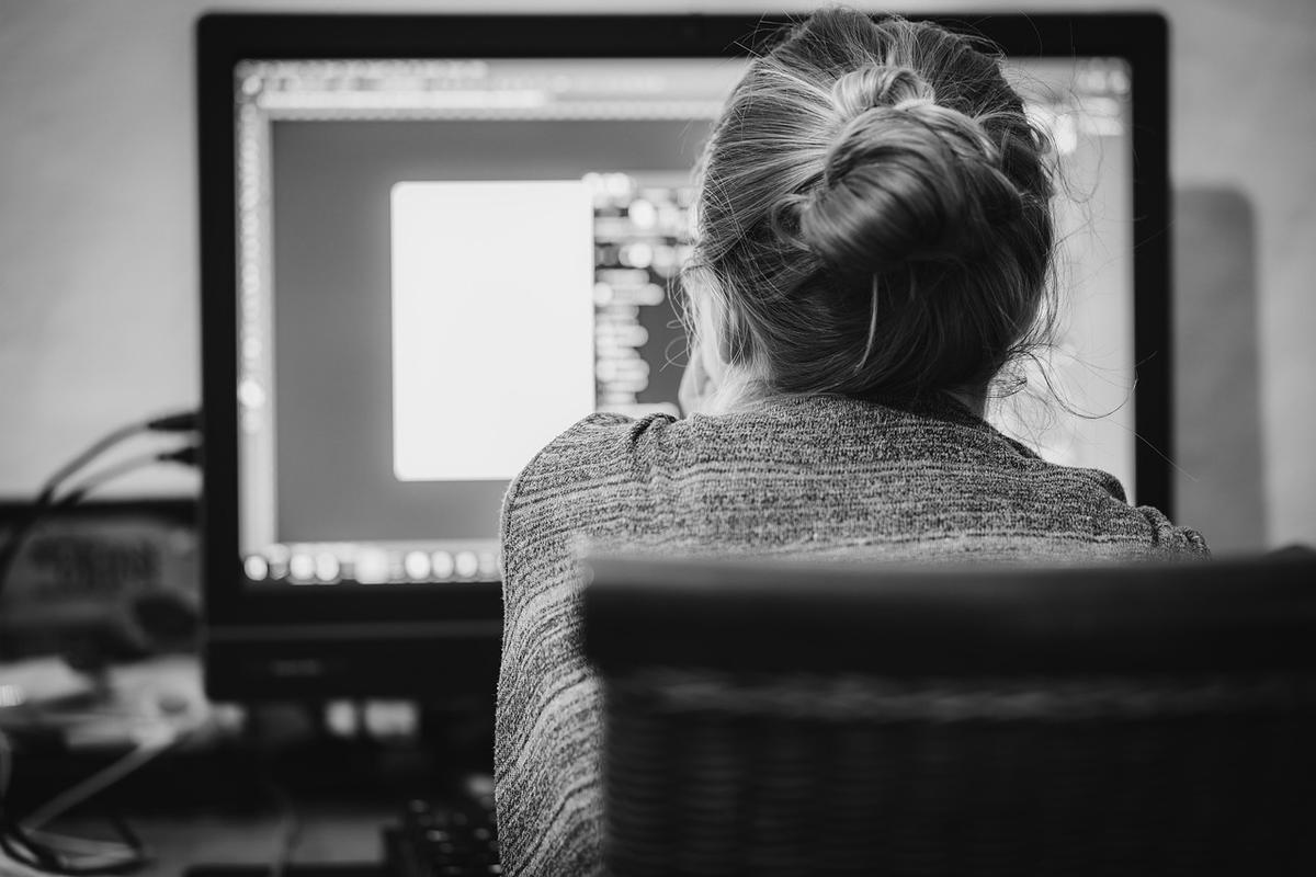 Développeur assis face à son écran d'ordinateur, de dos, en train de travailler