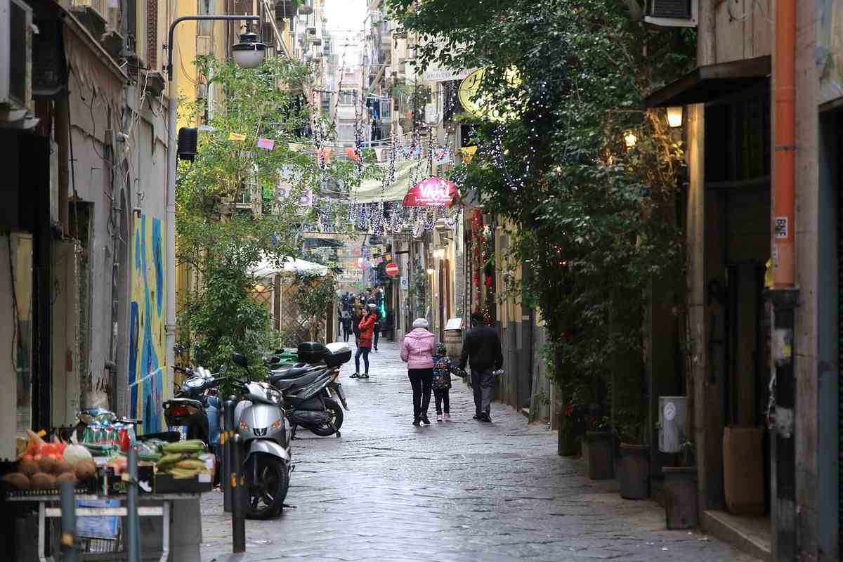 Piétons marchent dans une rue pavée bordée de boutiques et d'arbres
