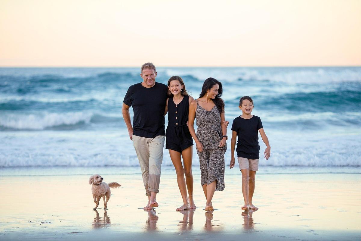 Famille et chien marchant sur la plage au coucher du soleil