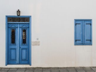 Porte et fenêtre bleues sur mur blanc avec lampe et pavés