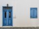 Porte et fenêtre bleues sur mur blanc avec lampe et pavés