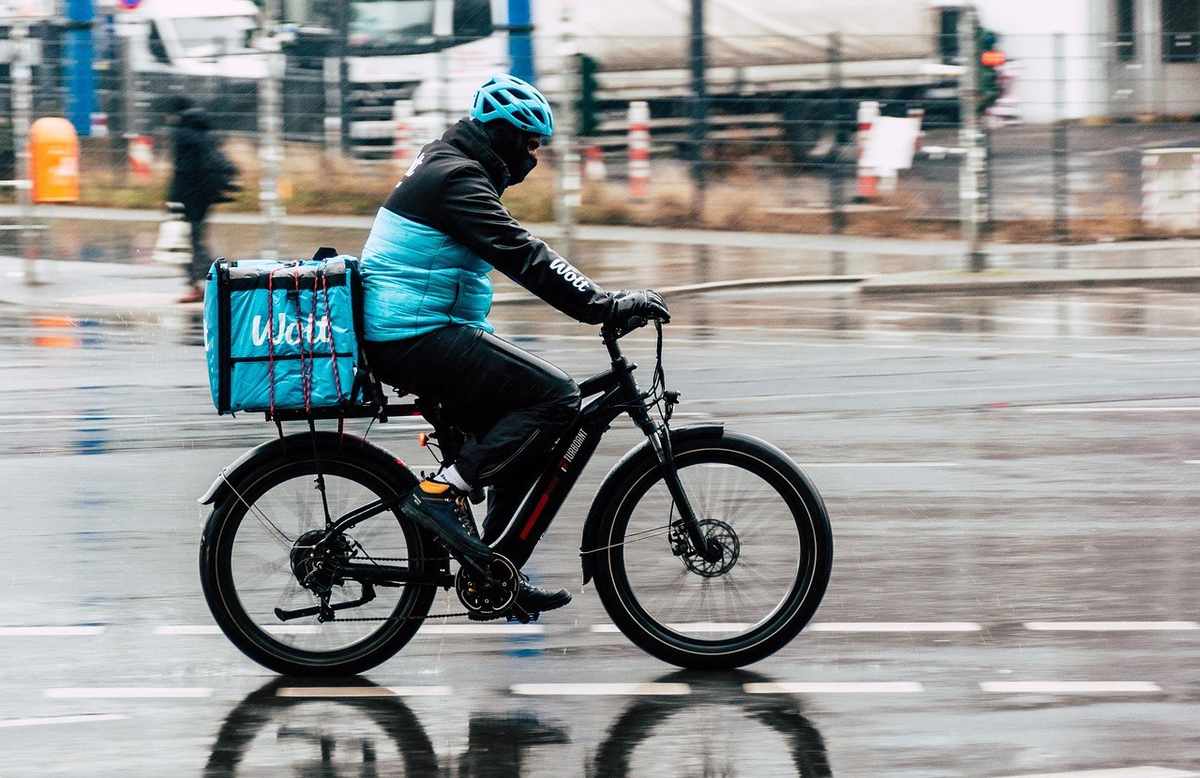 Livreur à vélo sur une rue mouillée, transporte un colis