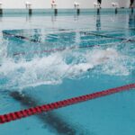 Nageur en pleine course dans une piscine, créant des éclaboussures d'eau
