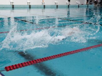 Nageur en pleine course dans une piscine, créant des éclaboussures d'eau