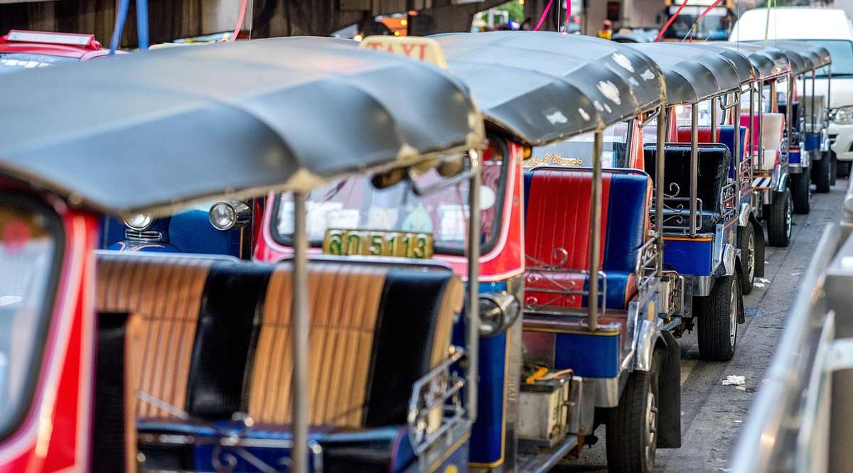 Ligne de tuk-tuks colorés stationnés le long d'une rue