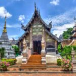 Un temple ornate avec stupa, jardins fleuris et visiteurs sous ciel bleu