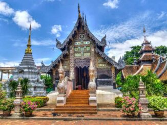 Un temple ornate avec stupa, jardins fleuris et visiteurs sous ciel bleu