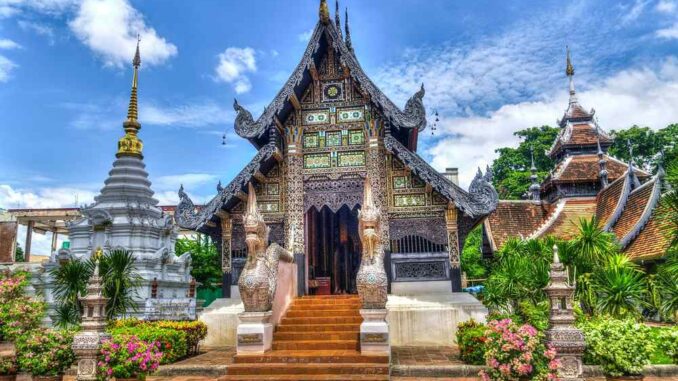 Un temple ornate avec stupa, jardins fleuris et visiteurs sous ciel bleu